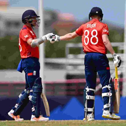 टी-20 वर्ल्ड कप मुकाबले में हैरी ब्रूक शतक पूरा करने के बाद जश्न मनाते हुए, पृष्ठभूमि में इंग्लैंड टीम के खिलाड़ी।