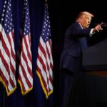 तस्वीर में अमेरिकी राष्ट्रपति डोनाल्ड ट्रम्प वॉशिंगटन में एक सार्वजनिक कार्यक्रम के दौरान मंच से संबोधित करते नजर आ रहे हैं।