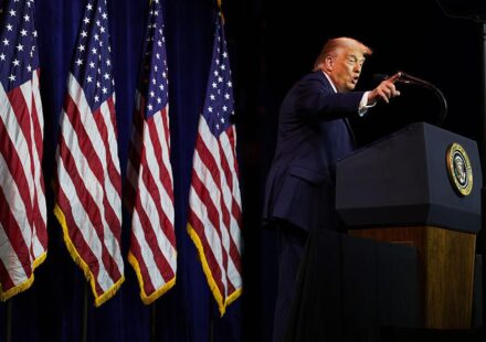 तस्वीर में अमेरिकी राष्ट्रपति डोनाल्ड ट्रम्प वॉशिंगटन में एक सार्वजनिक कार्यक्रम के दौरान मंच से संबोधित करते नजर आ रहे हैं।