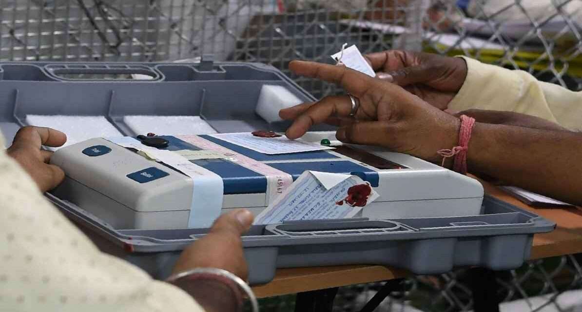 एक मतदान केंद्र पर ईवीएम मशीन की जांच करते हुए चुनाव अधिकारी, जिसमें बटन साफ और सुरक्षित दिखाई दे रहे हैं।