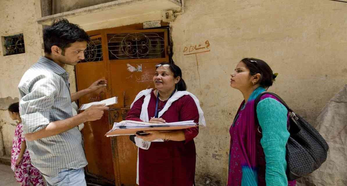 सरकारी टीम घर-घर जाकर परिवार की जानकारी जुटाते हुए, जनगणना सर्वे प्रक्रिया का दृश्य।