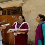 सरकारी टीम घर-घर जाकर परिवार की जानकारी जुटाते हुए, जनगणना सर्वे प्रक्रिया का दृश्य।