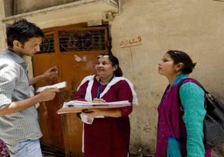 सरकारी टीम घर-घर जाकर परिवार की जानकारी जुटाते हुए, जनगणना सर्वे प्रक्रिया का दृश्य।