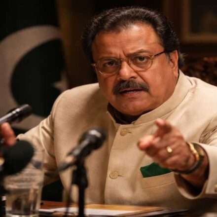 एक सीन जिसमें राकेश बेदी अपने किरदार में गंभीर और कॉमिक एक्सप्रेशन के साथ नजर आ रहे हैं, फिल्मी माहौल के साथ