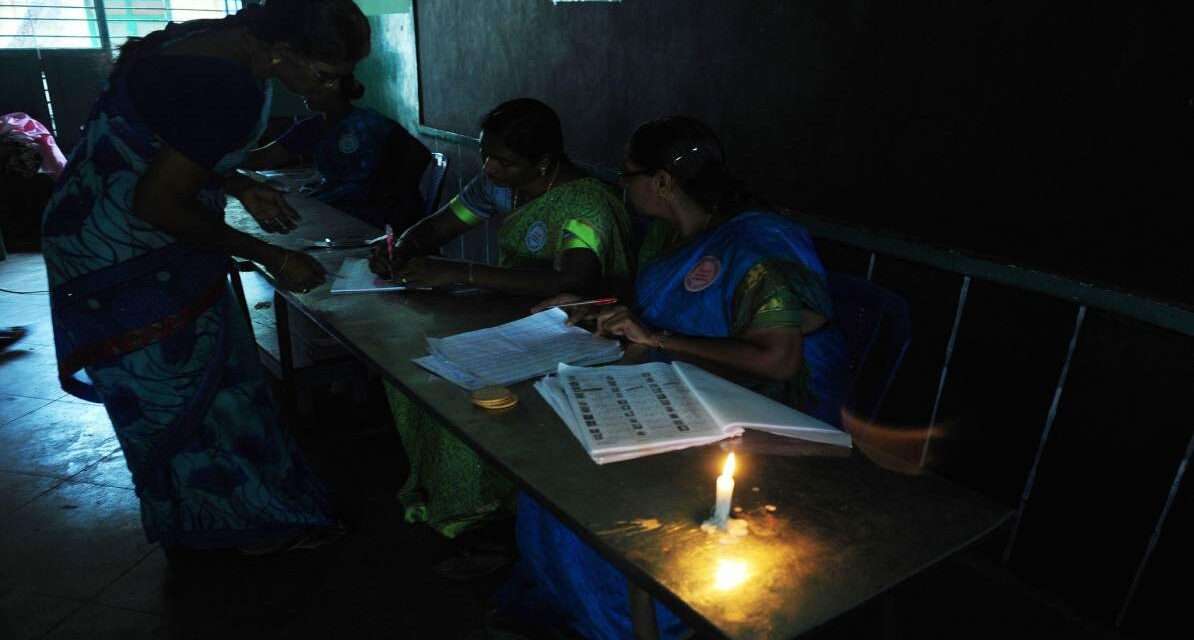 एक मतदान केंद्र जहां बिजली नहीं है और कम रोशनी में चुनाव की तैयारी की जा रही है