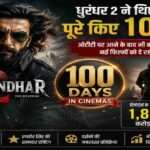 रणवीर सिंह की स्पाई थ्रिलर फिल्म धुरंधर 2 का सिनेमाई पोस्टर, जिसमें एक्शन बैकग्राउंड और 100 Days Success का सिनेमाई माहौल दिखाया गया है।